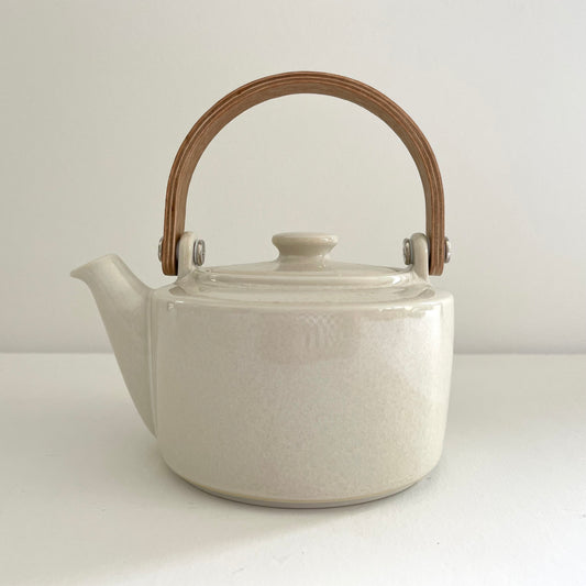white ceramic Japanese tea pot with bent wood handle and stainless steel strainer