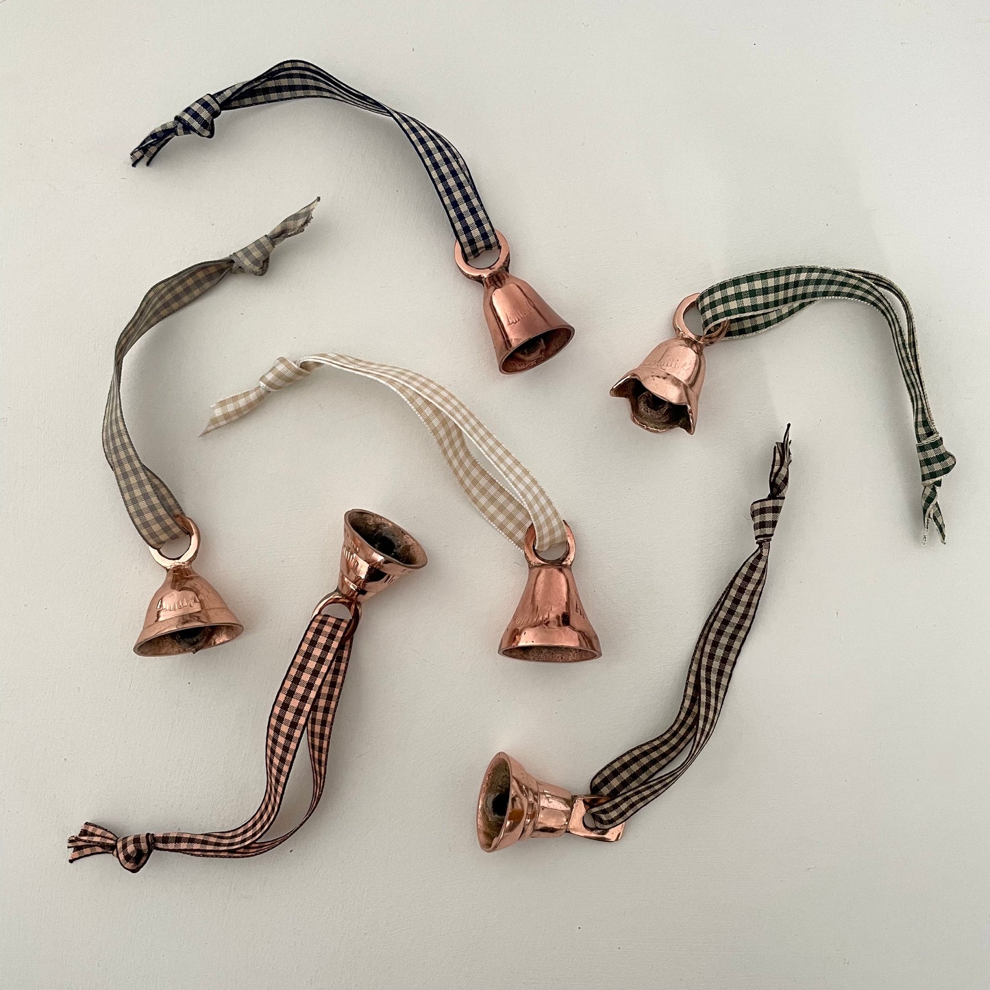 1 1/2" copper flared and tulip shaped bells made in India and strung on 33 colors of gingham ribbon to make a Christmas holiday ornament