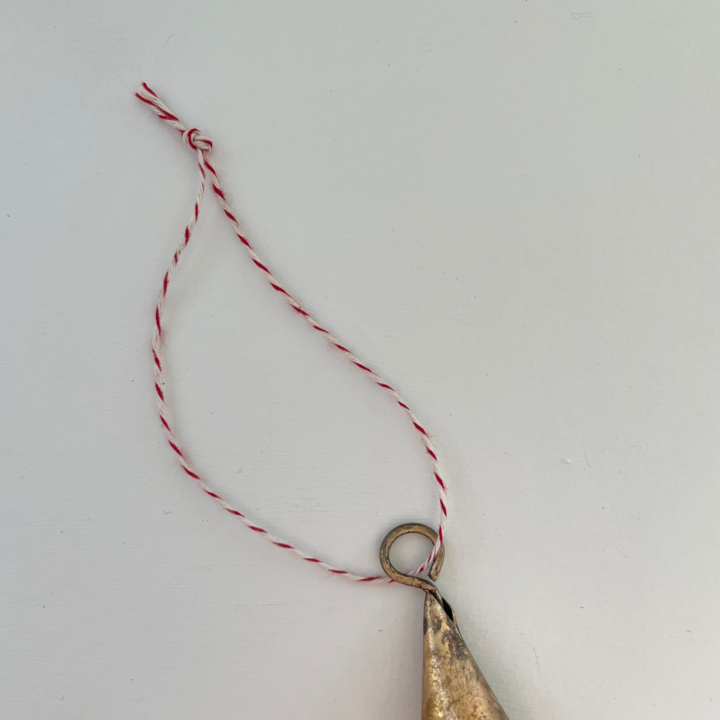 tiny 2 inch cone shaped tin bells with brass finish Christmas holiday ornaments on red and white striped bakers twine