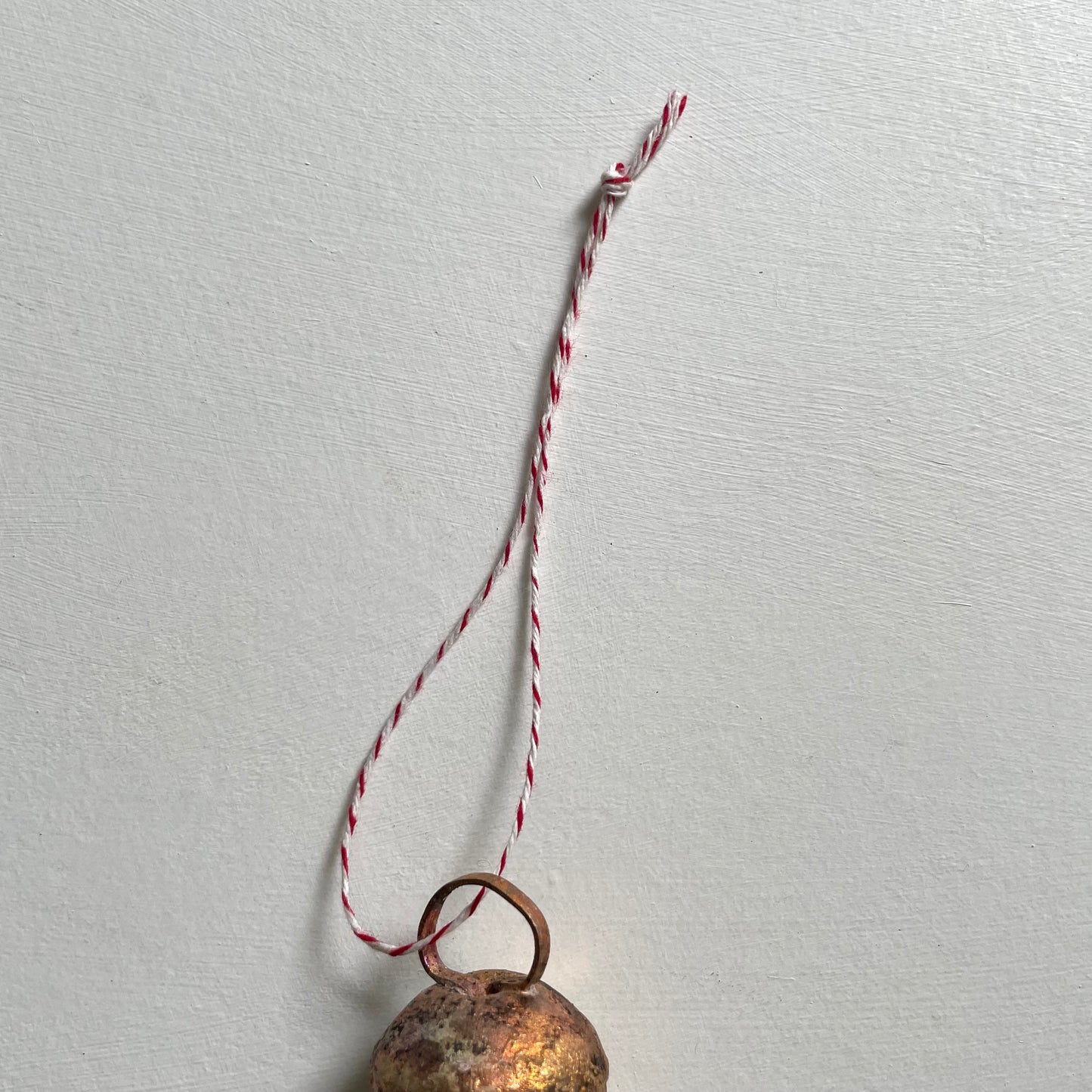 tiny rounded top tin bells with brass finish Christmas holiday ornaments on red and white bakers twine