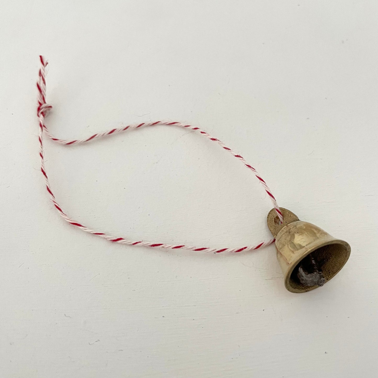 7/8" mini brass flared bell ornament on striped red and white bakers twine