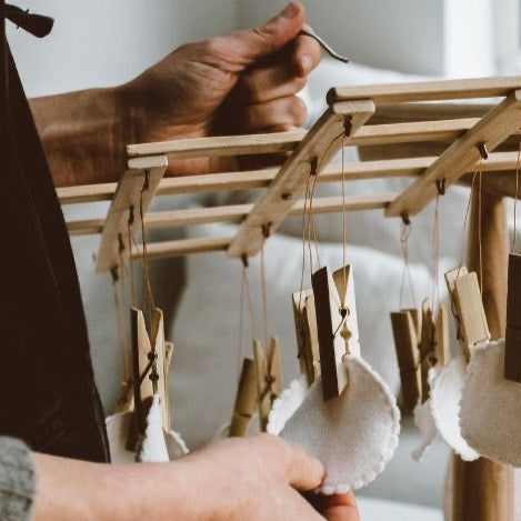 eco bamboo hanging laundry drying rack with clothespins holding reusable beauty rounds