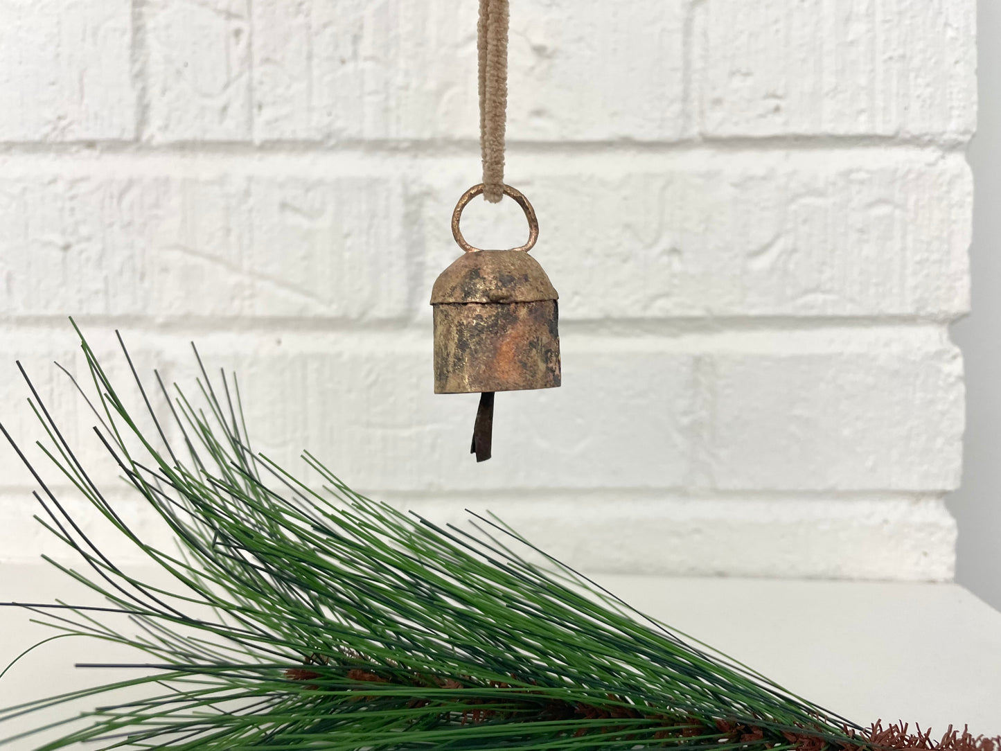 rustic tin bell with brass finish and metal striker hung on sueded cord for a Christmas ornament