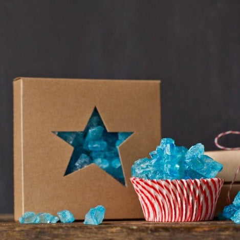 individual tan kraft cardboard cookie boxes with star cutout window next to red and white striped cupcake liners filled with candy