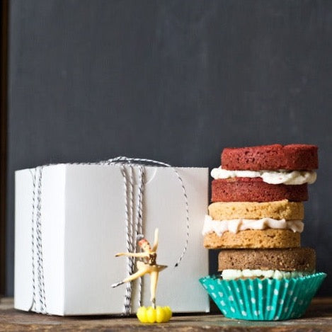 retro ballernina cupcake toppers sitting next to a stack of whoopie pies, square bakery box, and a mason jar of milk