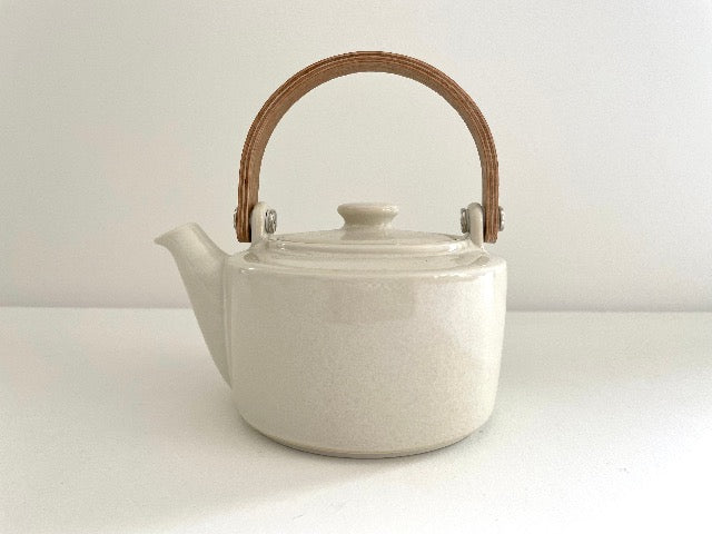 white ceramic Japanese tea pot with bent wood handle and stainless steel strainer