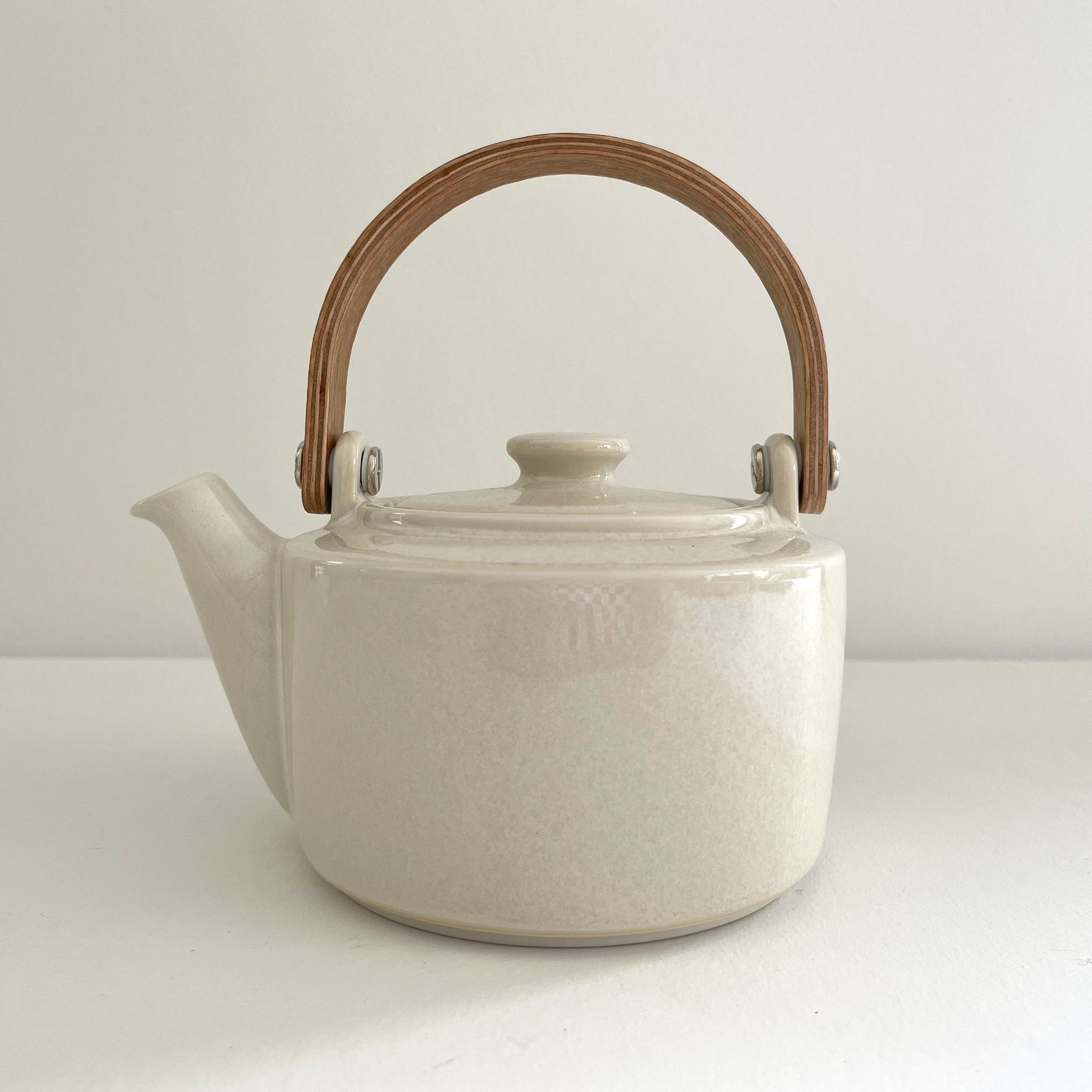 white ceramic Japanese tea pot with bent wood handle and stainless steel strainer