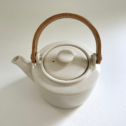 white ceramic Japanese tea pot with bent wood handle and stainless steel strainer