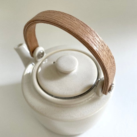 white ceramic Japanese tea pot with bent wood handle and stainless steel strainer