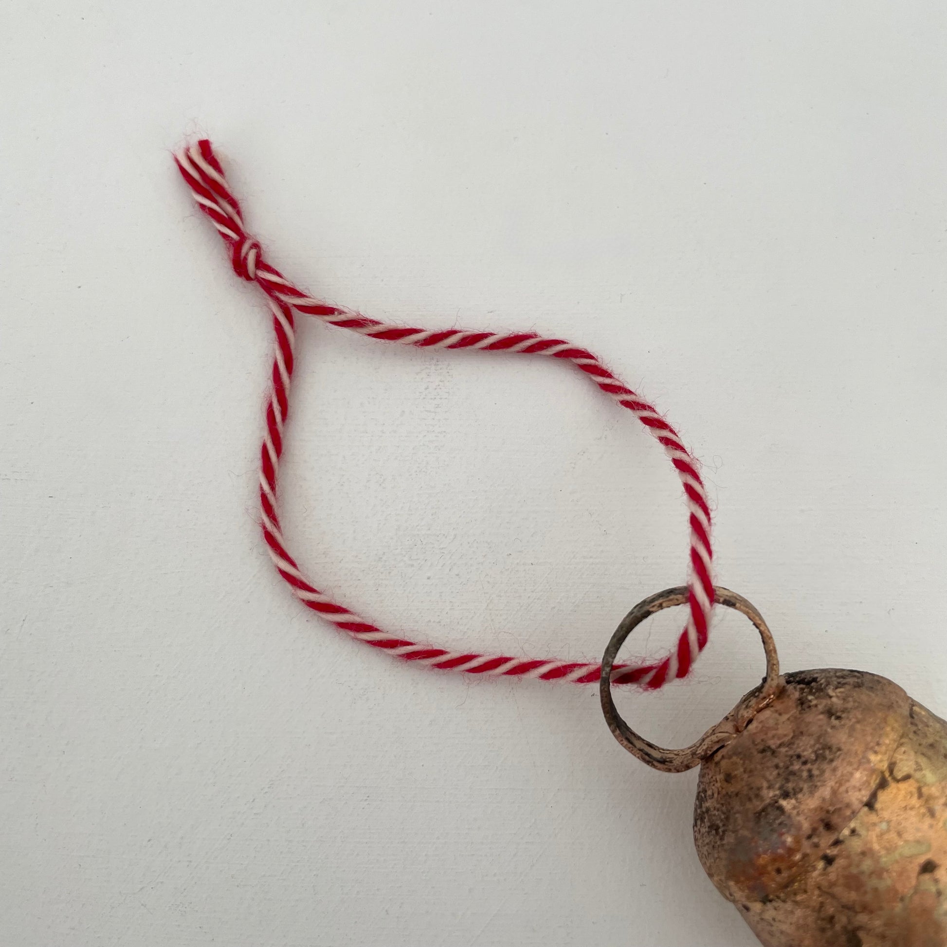 2 1/4" rustic rounded top tin bell with brass finish ornament on red and white cotton twine