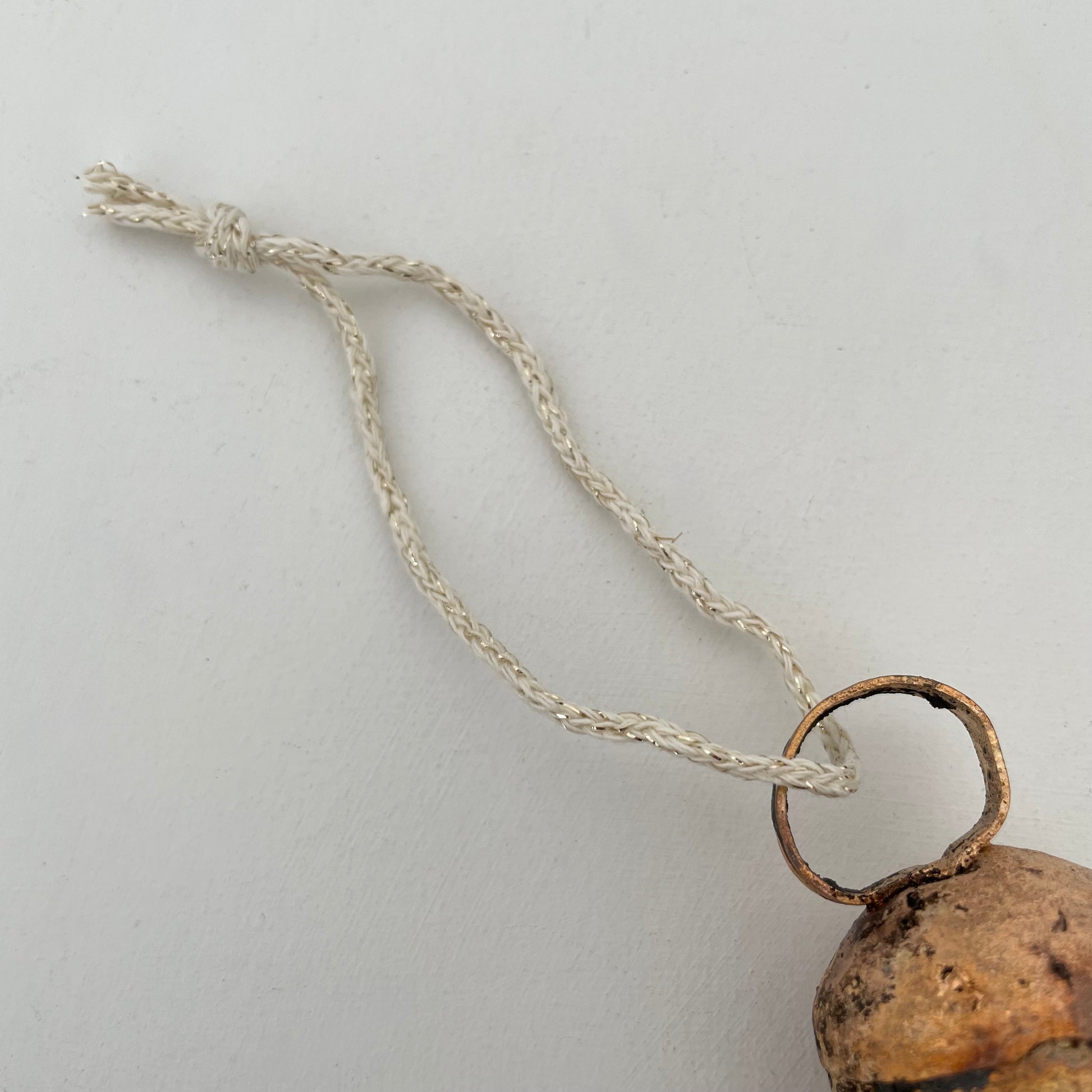 2 1/4" rustic rounded top tin bell with brass finish ornament on cream and gold sweater knit