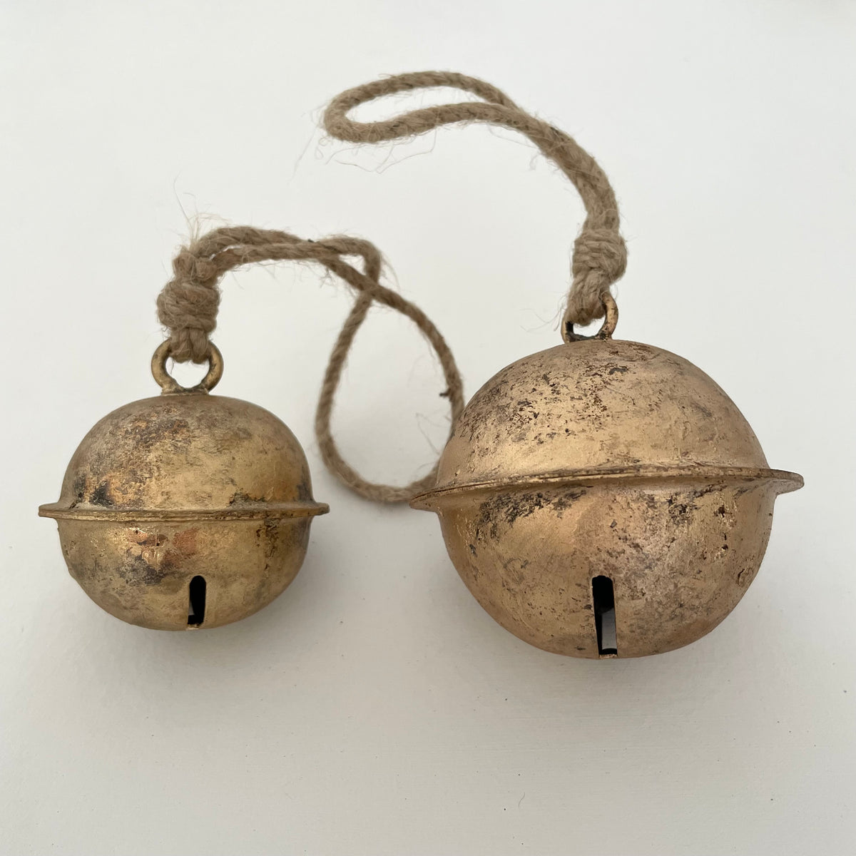 comparison in size of 2 1/2" and 3" rustic cross-cut tin sleigh bell with brass finish and jute hanger