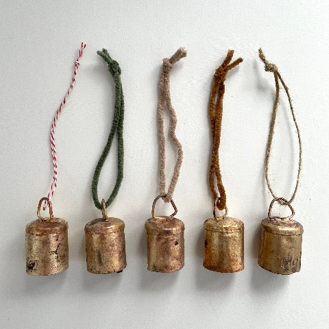 1 3/4 inch flat top tin bell with brass finish strung on twine suede and jute to make an ornament