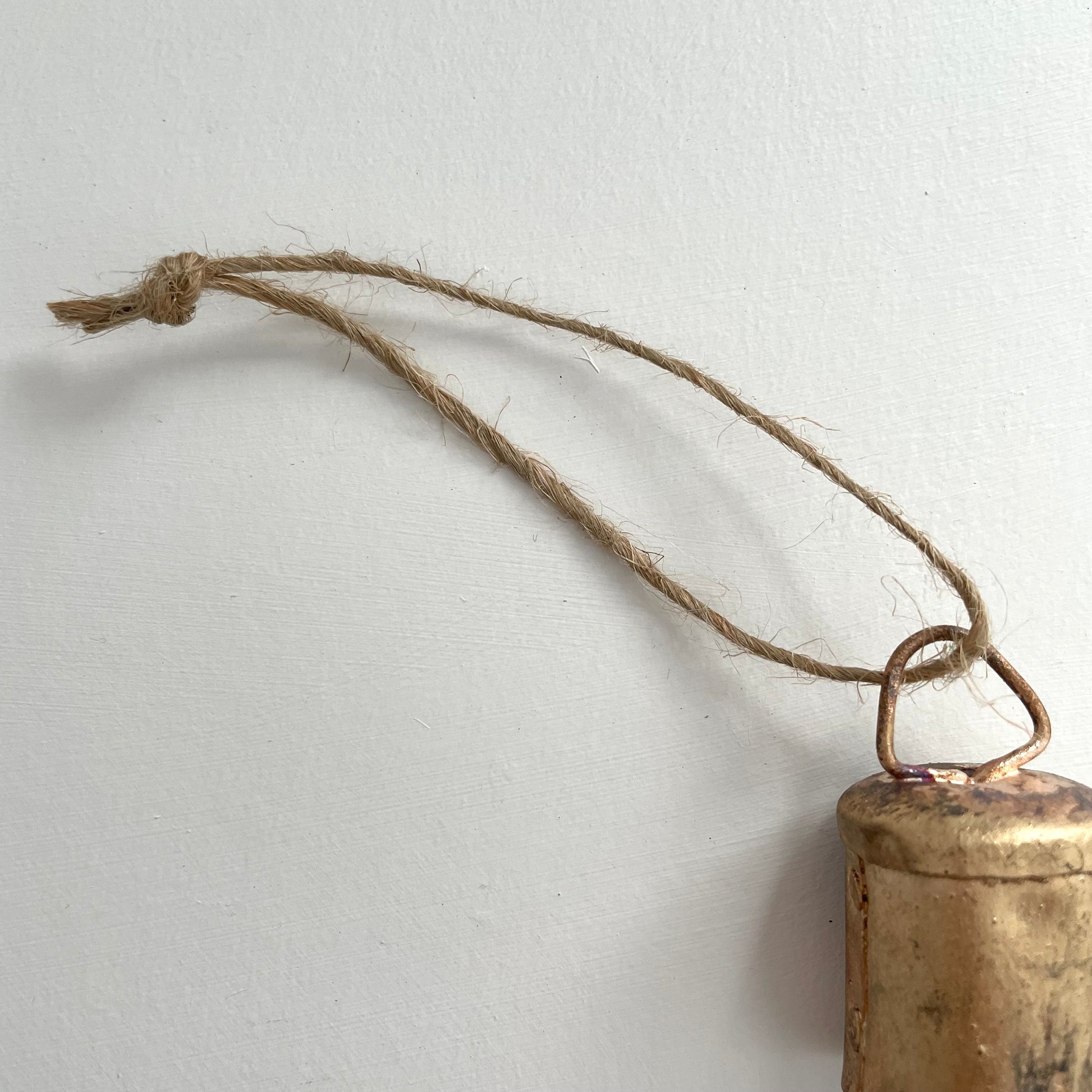 1 3/4 inch flat top tin bell with brass finish strung on twine suede and jute to make an ornament with jute cord
