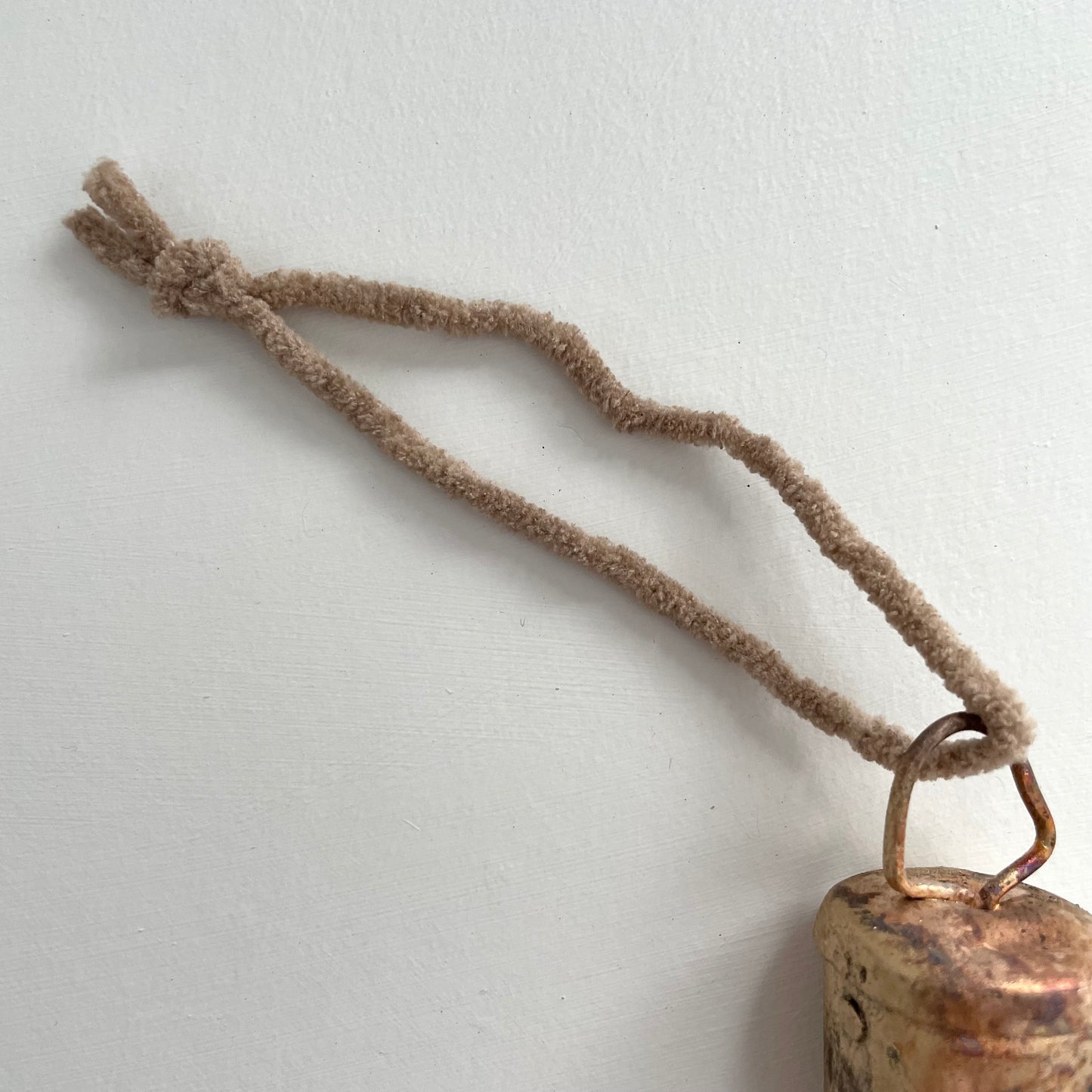 1 3/4 inch flat top tin bell with brass finish strung on twine suede and jute to make an ornament with tan suede cord