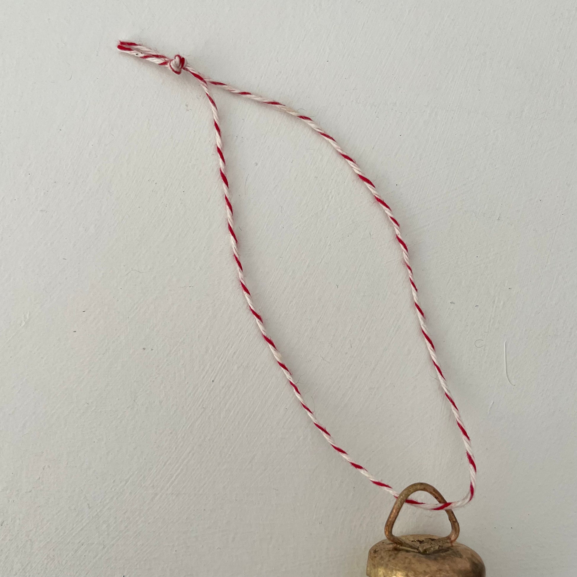 1 1/4 inch flat top tin bell with brass finish handmade ornament on red and white striped bakers twine