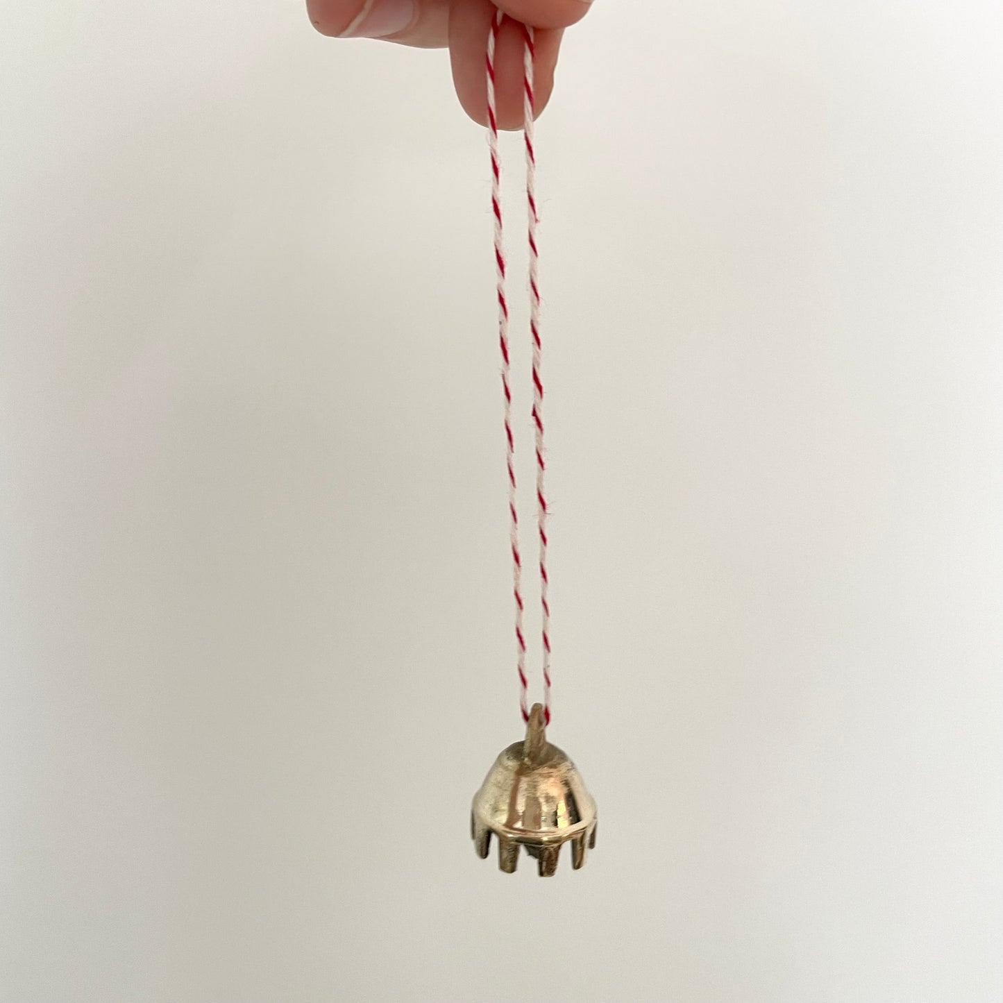 7/8" mini brass claw bell ornament on red and white striped bakers twine