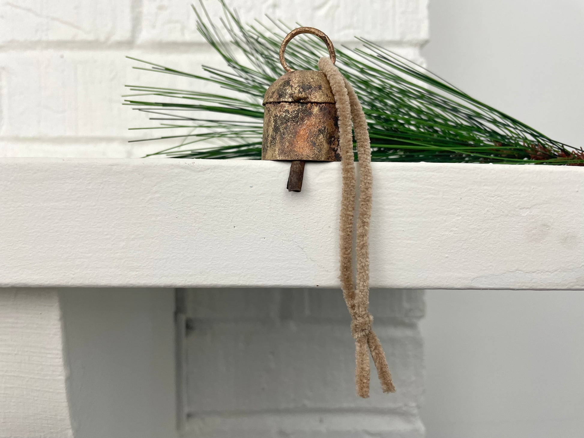 rustic tin bell with brass finish and metal striker hung on sueded cord for a Christmas ornament