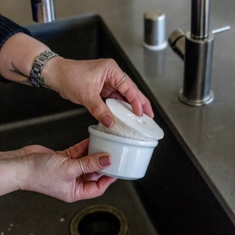 eco and sustainable solid dish soap in white porcelain bowl with refill available for a farmhouse kitchen