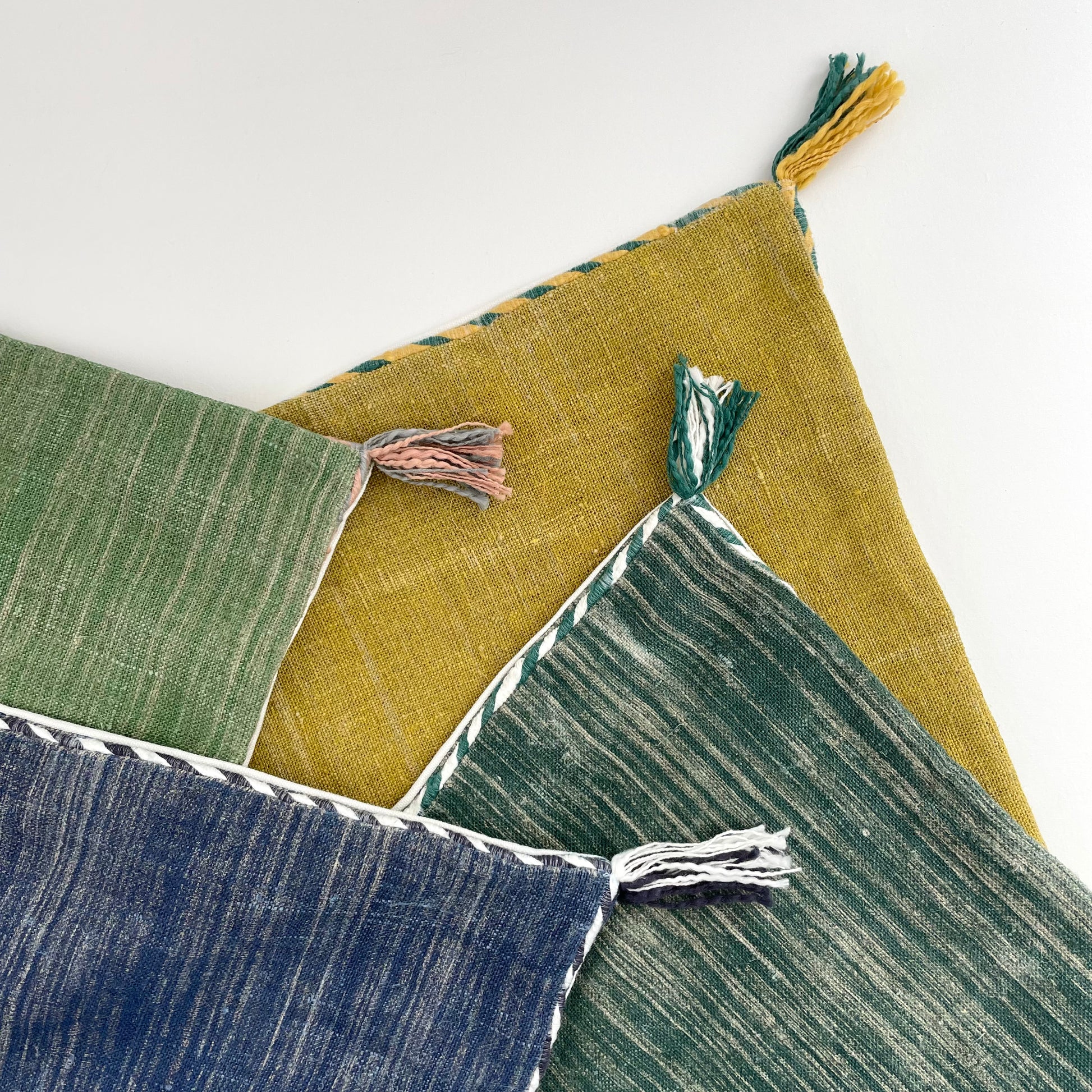 linen pillow covers in mustard, blue, and green with striped edging and tassels