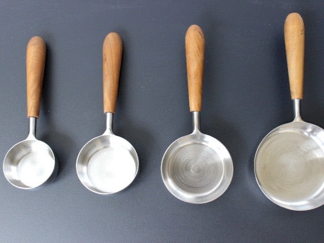 teak wood and stainless steel measuring cups for a simple utilitarian kitchen