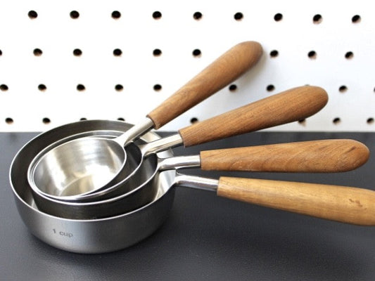 teak wood and stainless steel measuring cups for a simple utilitarian kitchen