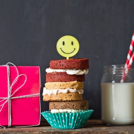 bright fluorescent lime green happy face 60's cupcake toppers party supplies in a stack of whoopie pies