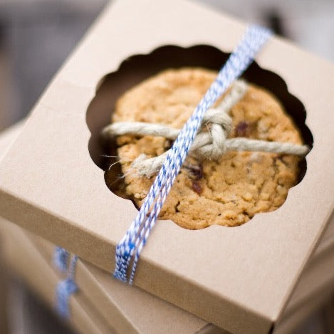 individual tan kraft cardboard cookie boxes with circle scallop cutout window wrapped with navy blue and white striped bakers twine